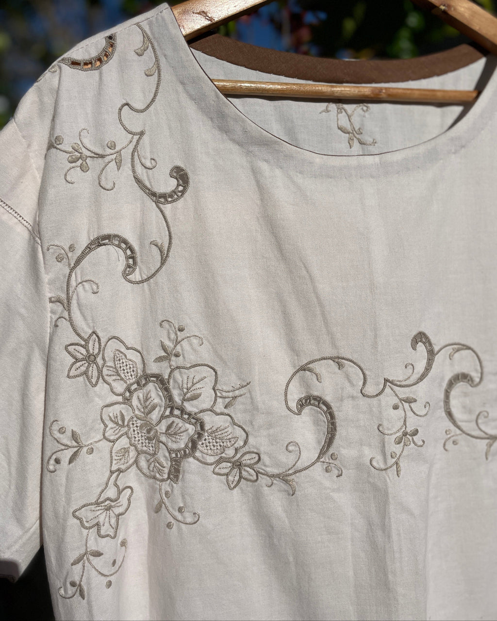 Light gray blouse with floral embroidery on a hanger