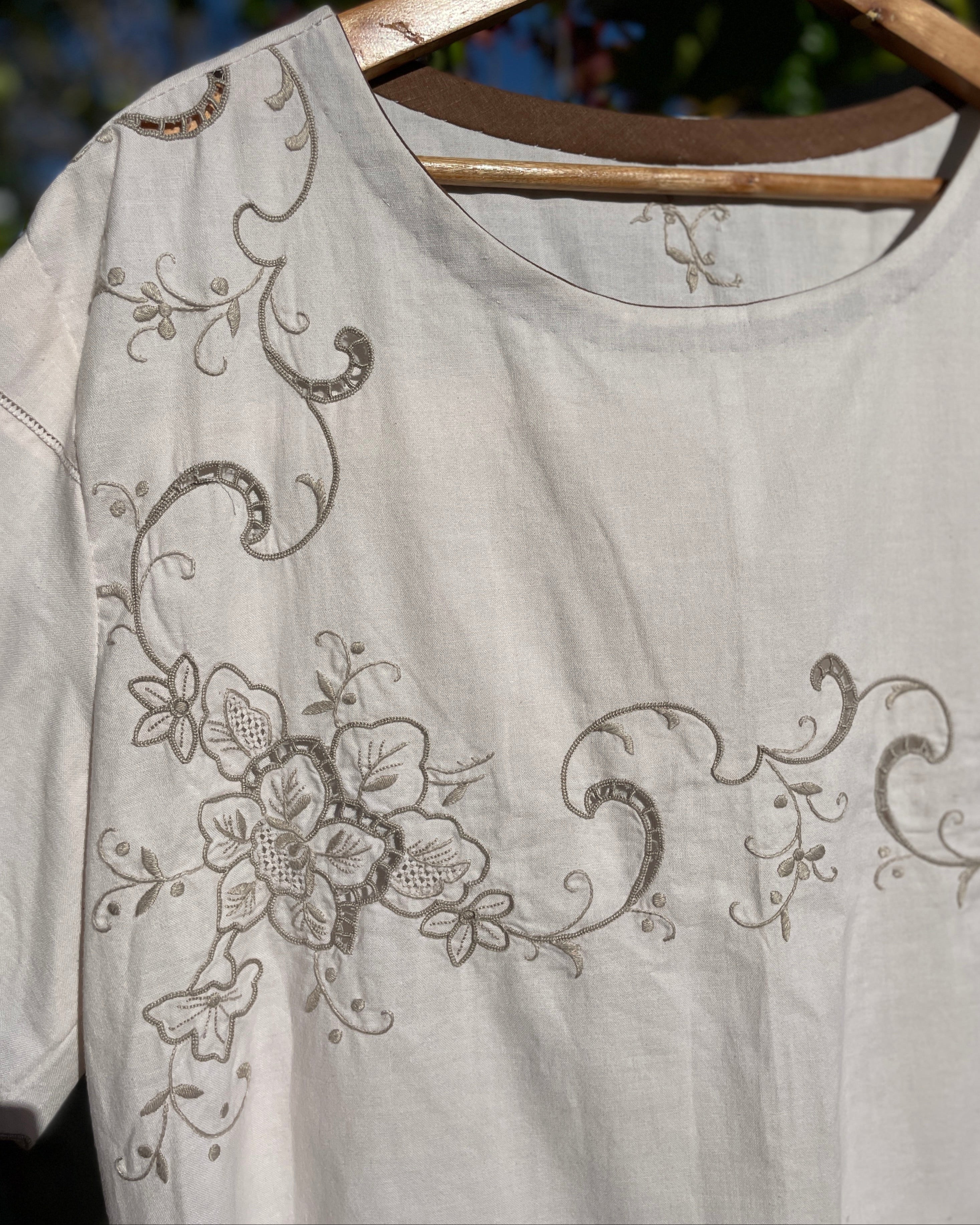Light gray blouse with floral embroidery on a hanger