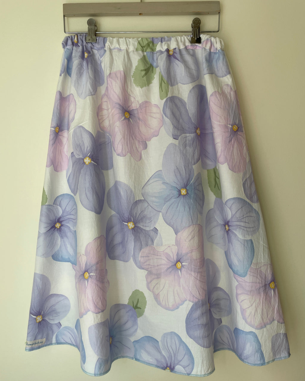 Floral patterned skirt on a metal rod against a beige wall