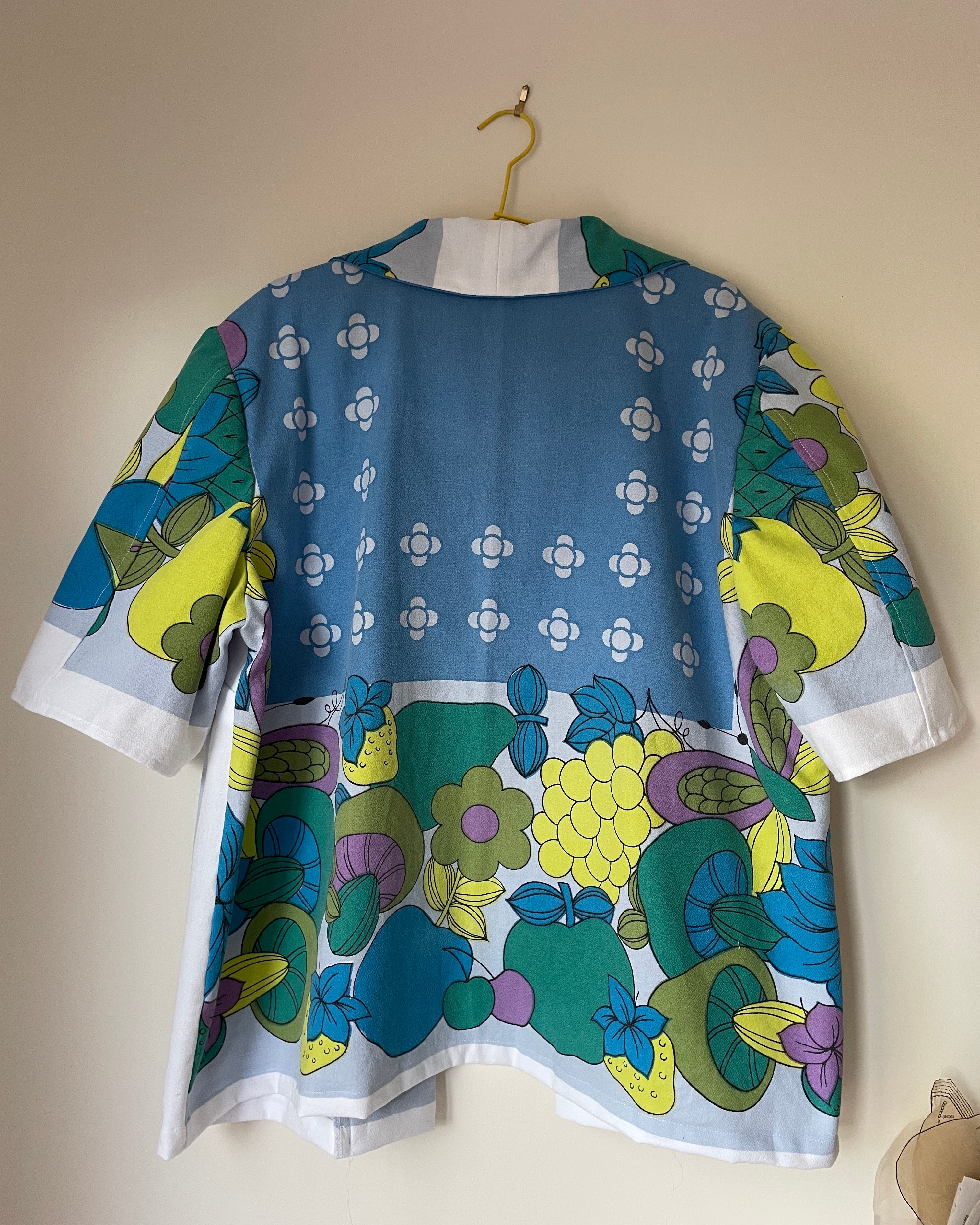 Colorful floral-patterned jacket on a hanger against a beige wall