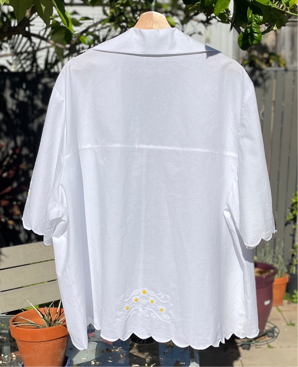 White blouse with lace details on a mannequin against a garden background