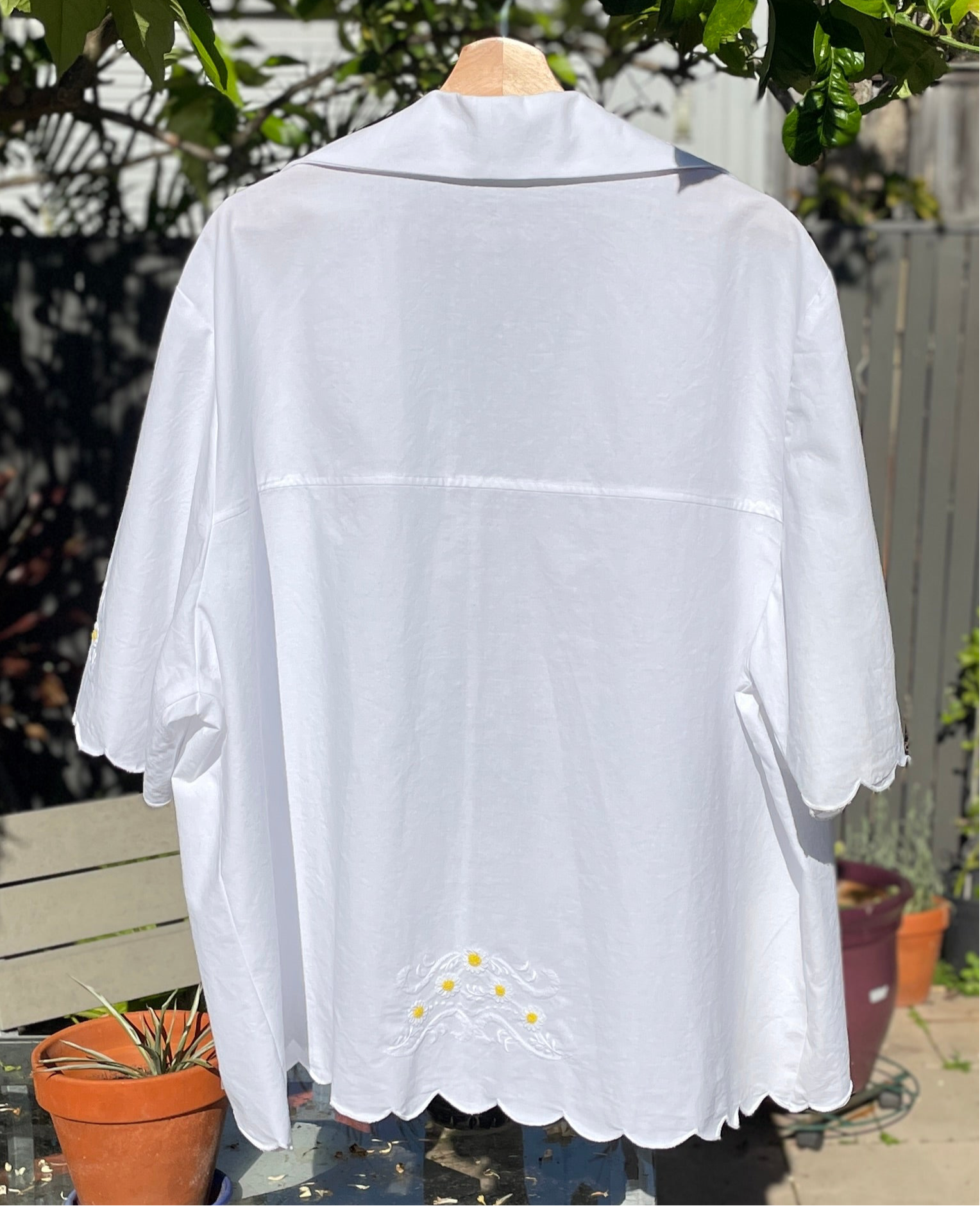 White blouse with lace details on a mannequin against a garden background