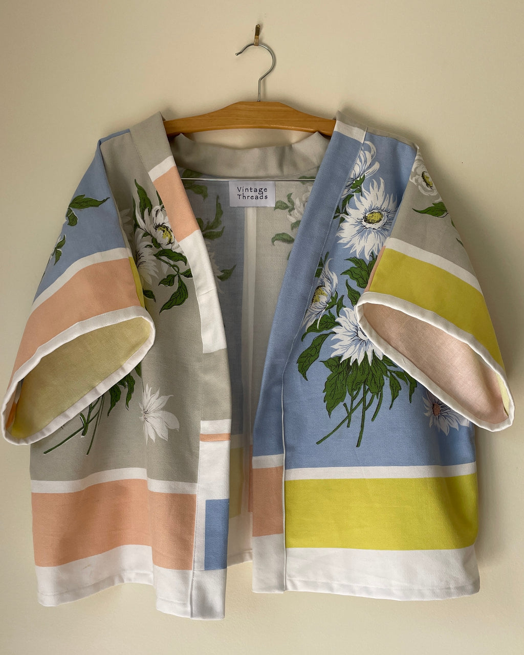 Floral-patterned kimono draped over a hanger against a plain background