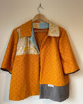 Orange patterned jacket on a hanger against a white background