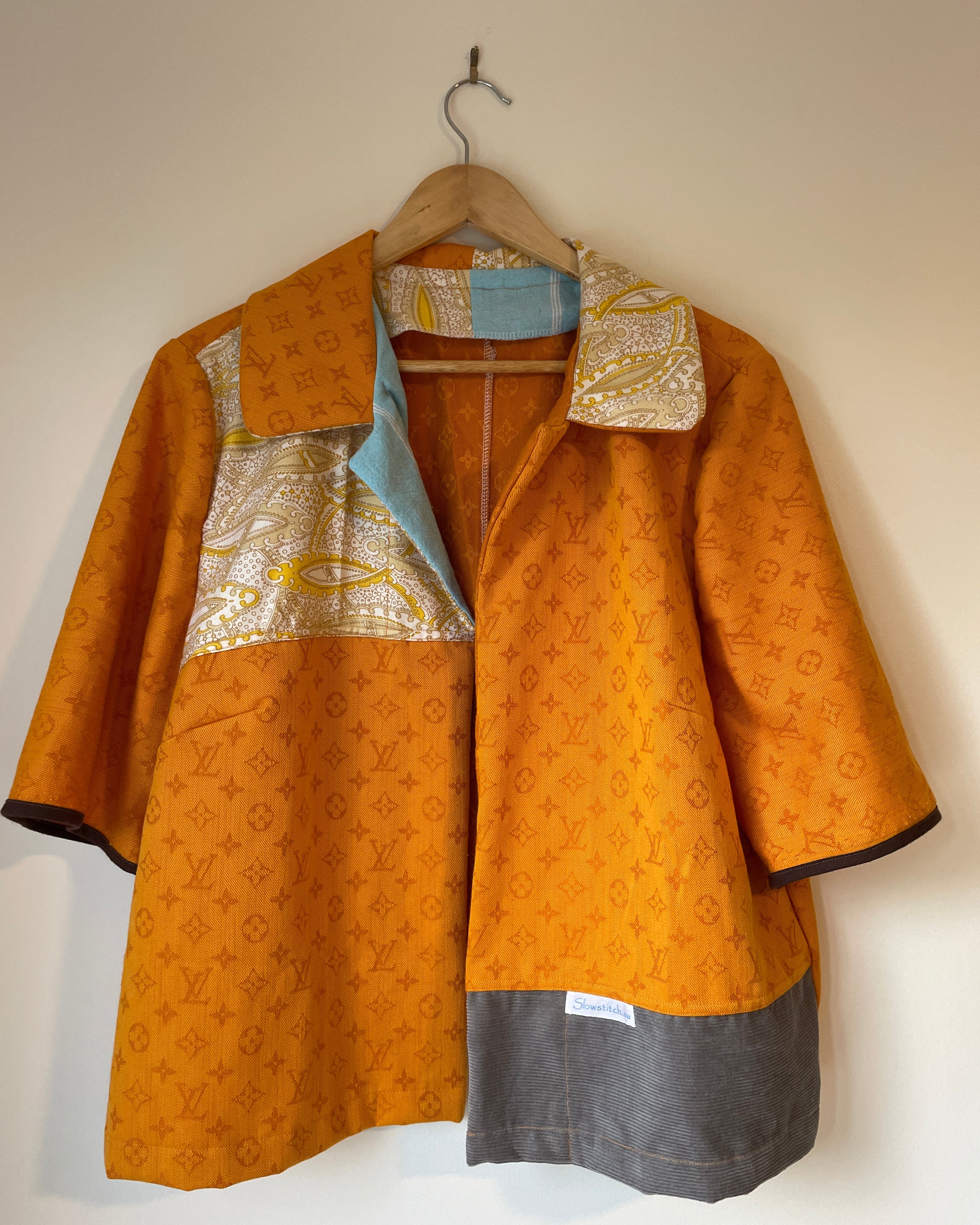 Orange patterned jacket on a hanger against a white background