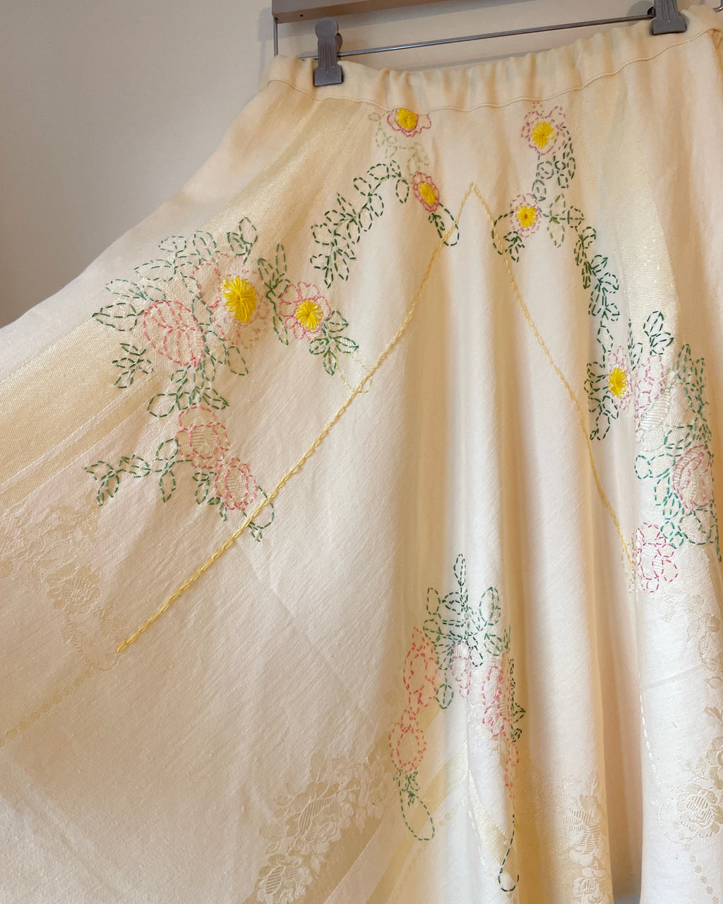 Embroidered dress with floral patterns on a wooden hanger.