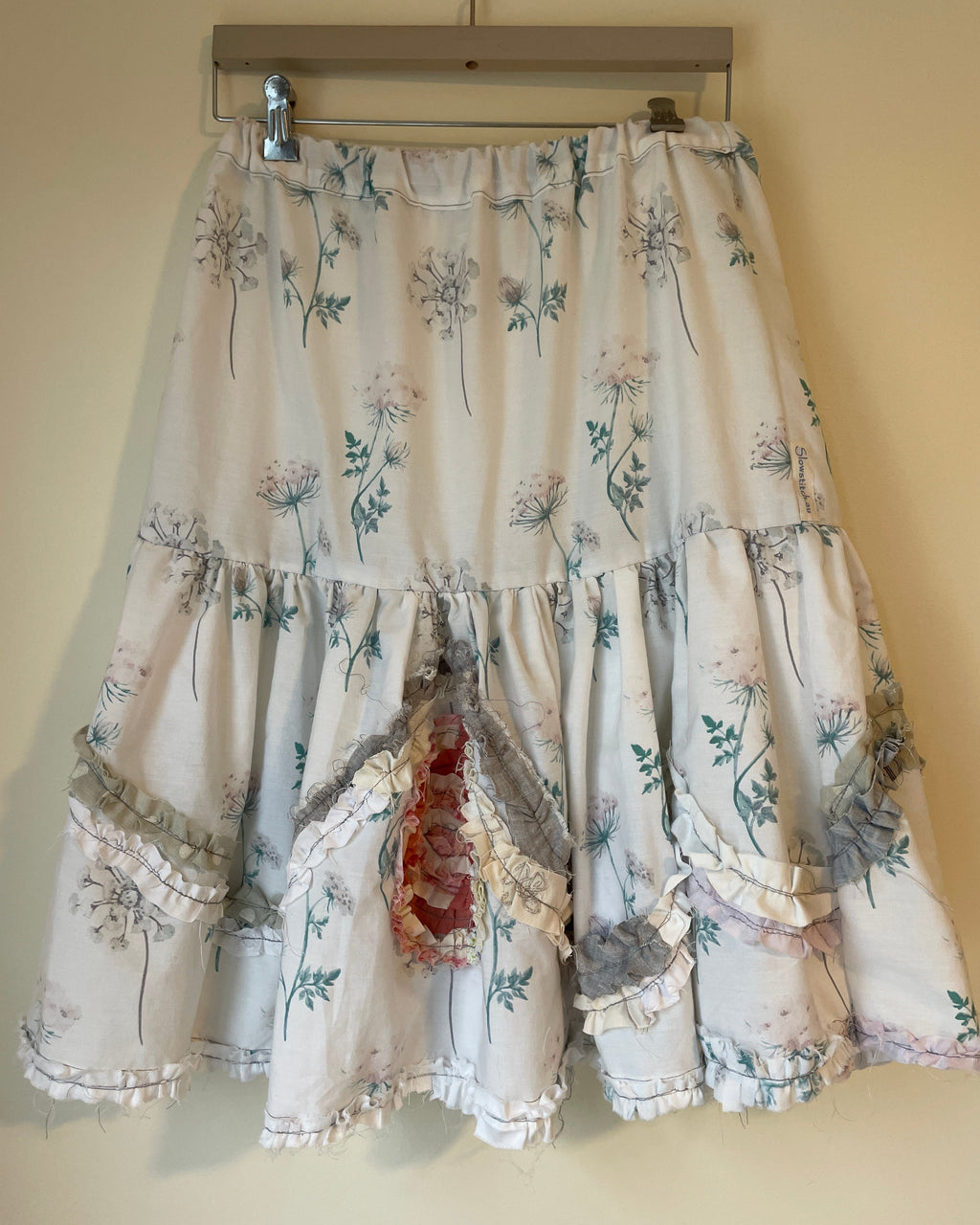 Floral patterned dress on a hanger against a beige wall
