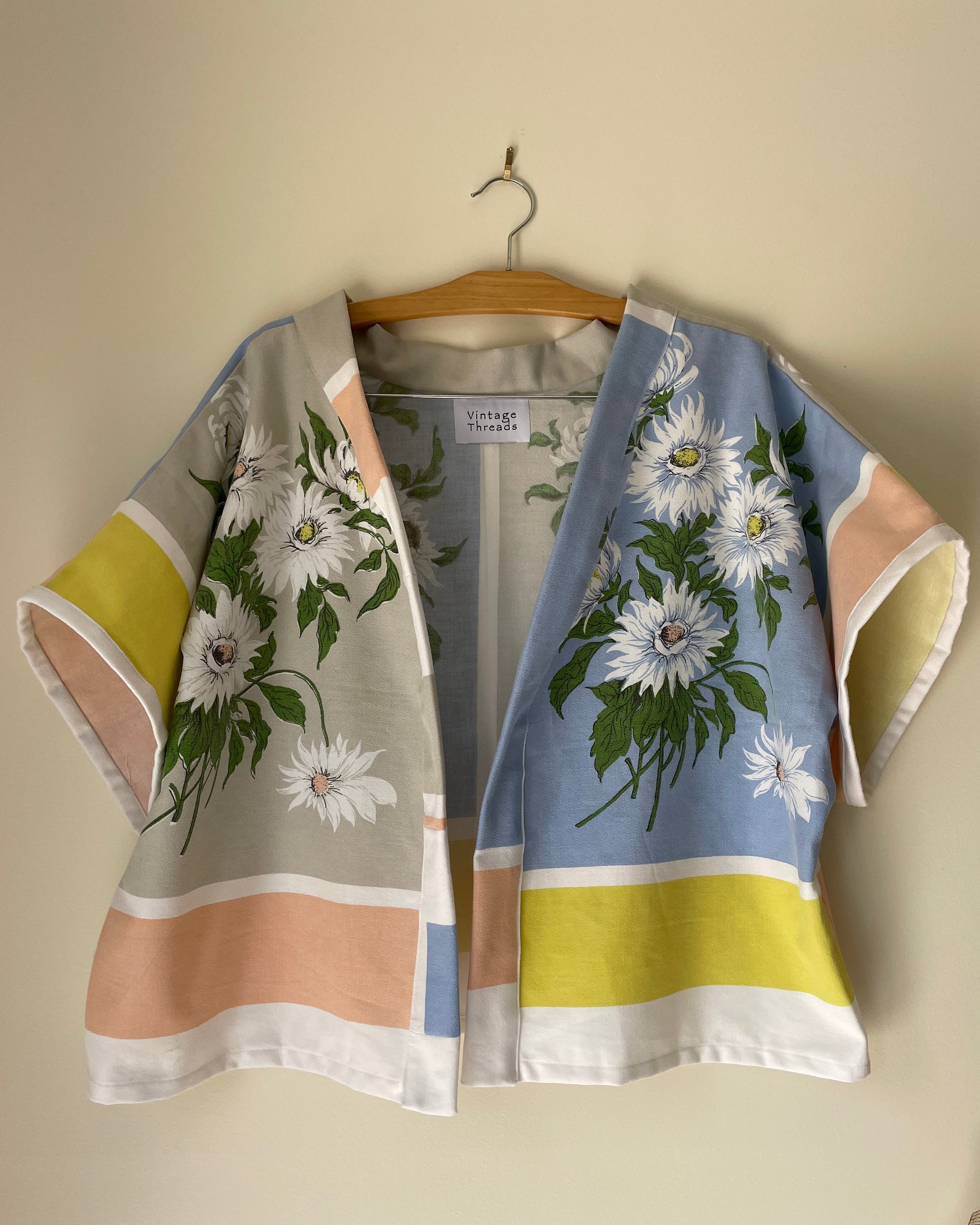 Floral kimono-style garment on a hanger against a beige wall