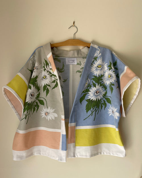 Floral kimono-style garment on a hanger against a beige wall