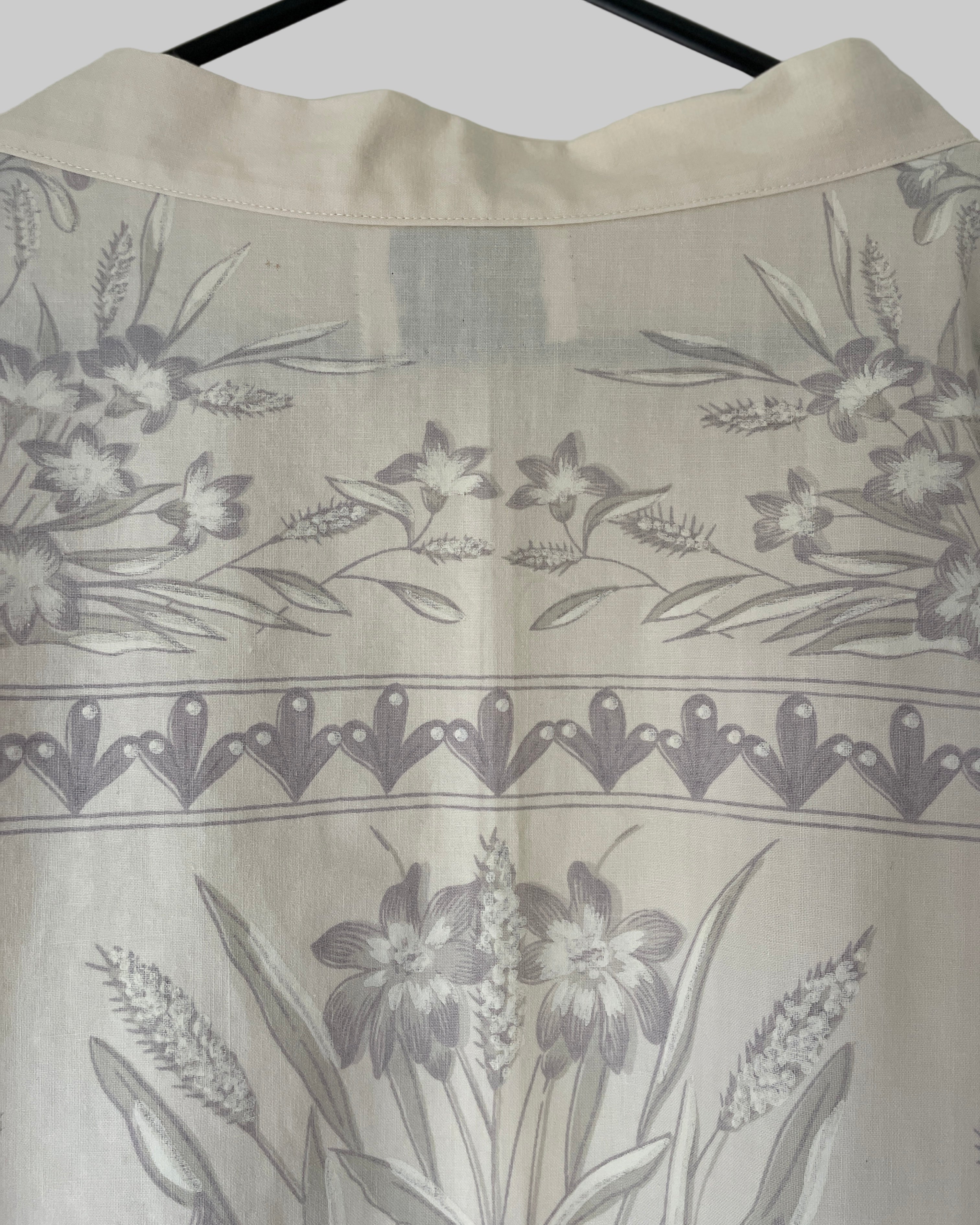 Greyish floral patterned fabric with a border design on a cream background