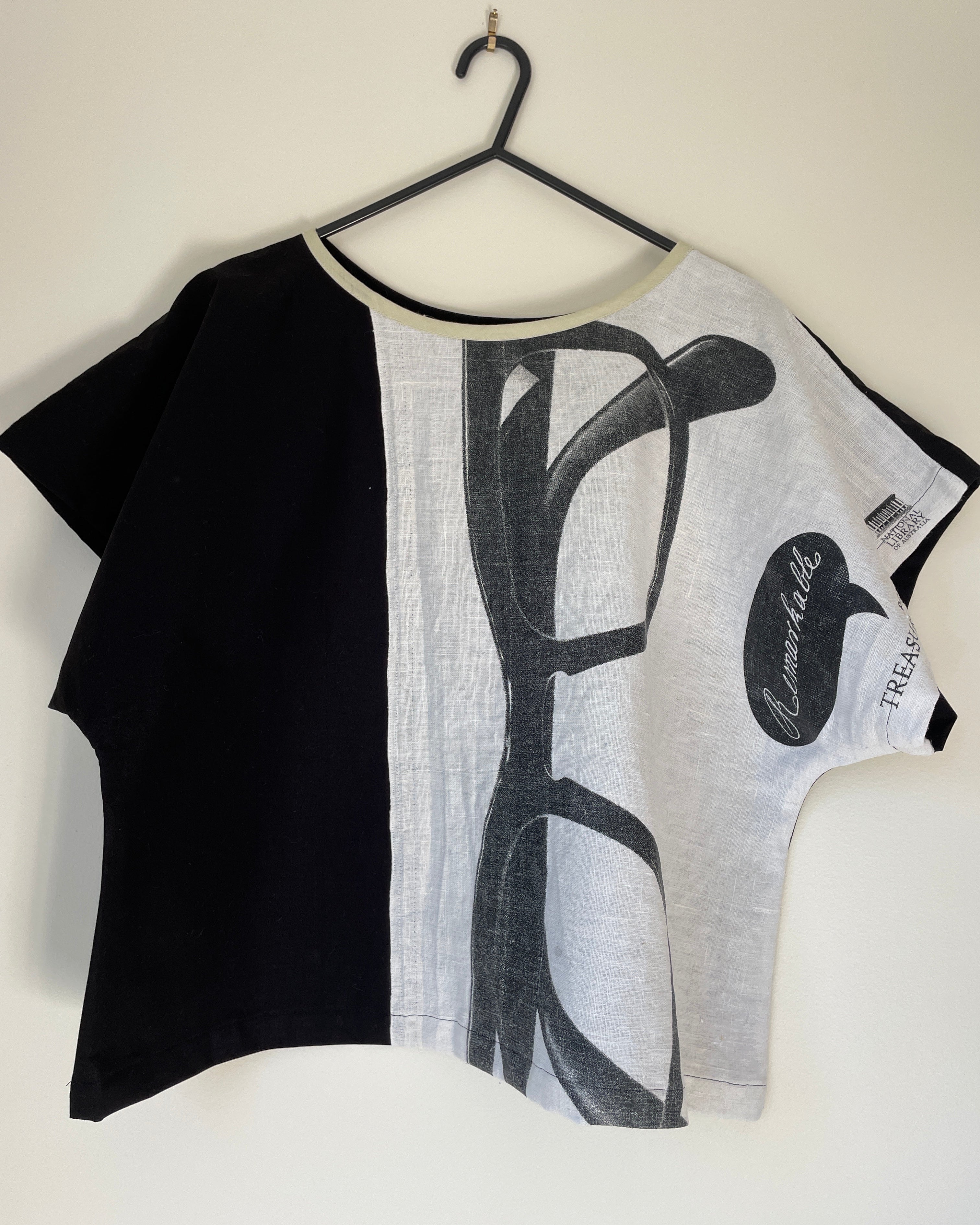 Black and white boxy top on a hanger with a visible brand label.