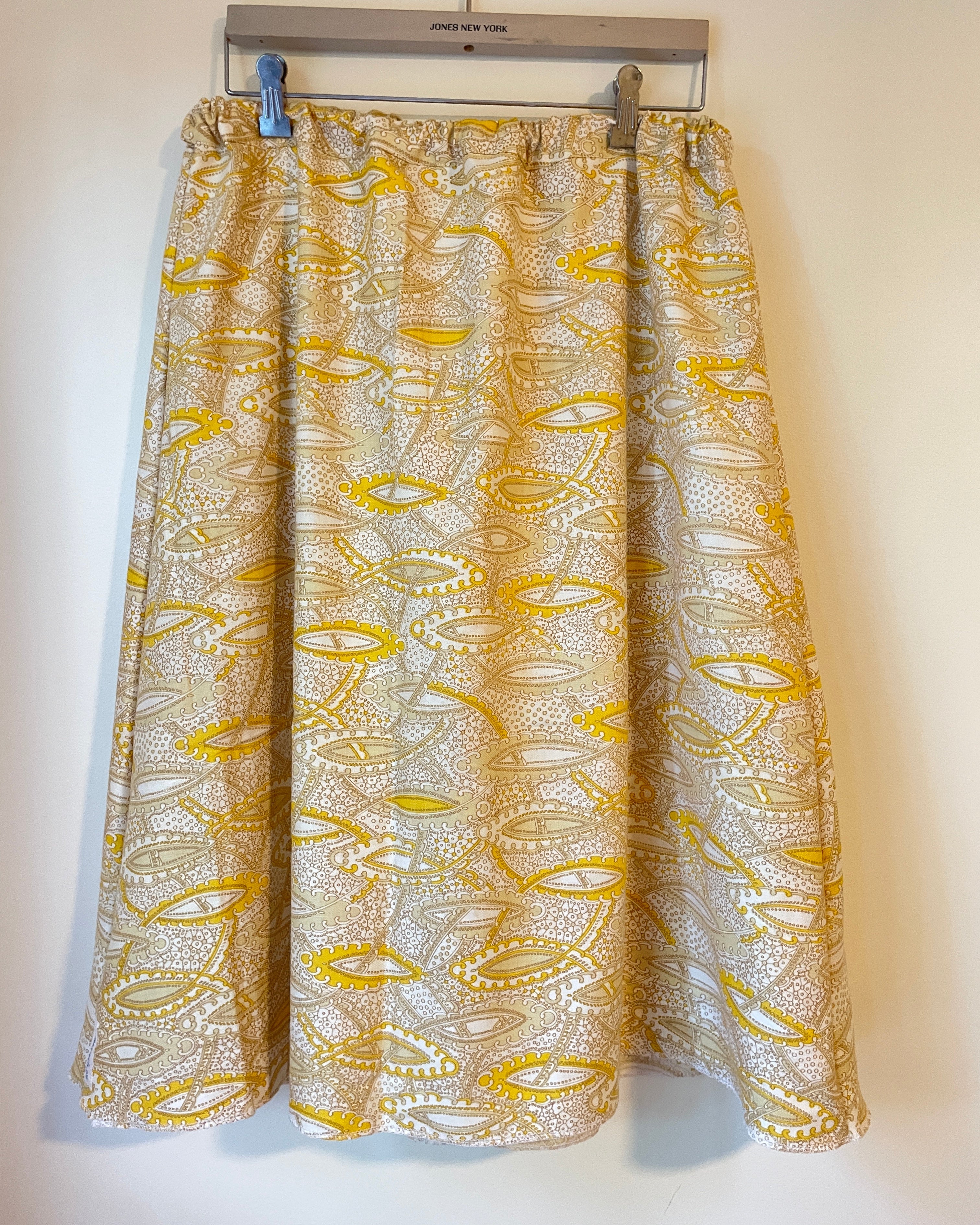 A shaped skirt with a gold and white pattern on a white background