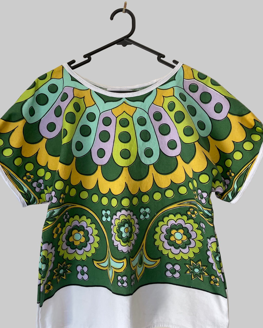 Colorful patterned top on a hanger against a white background
