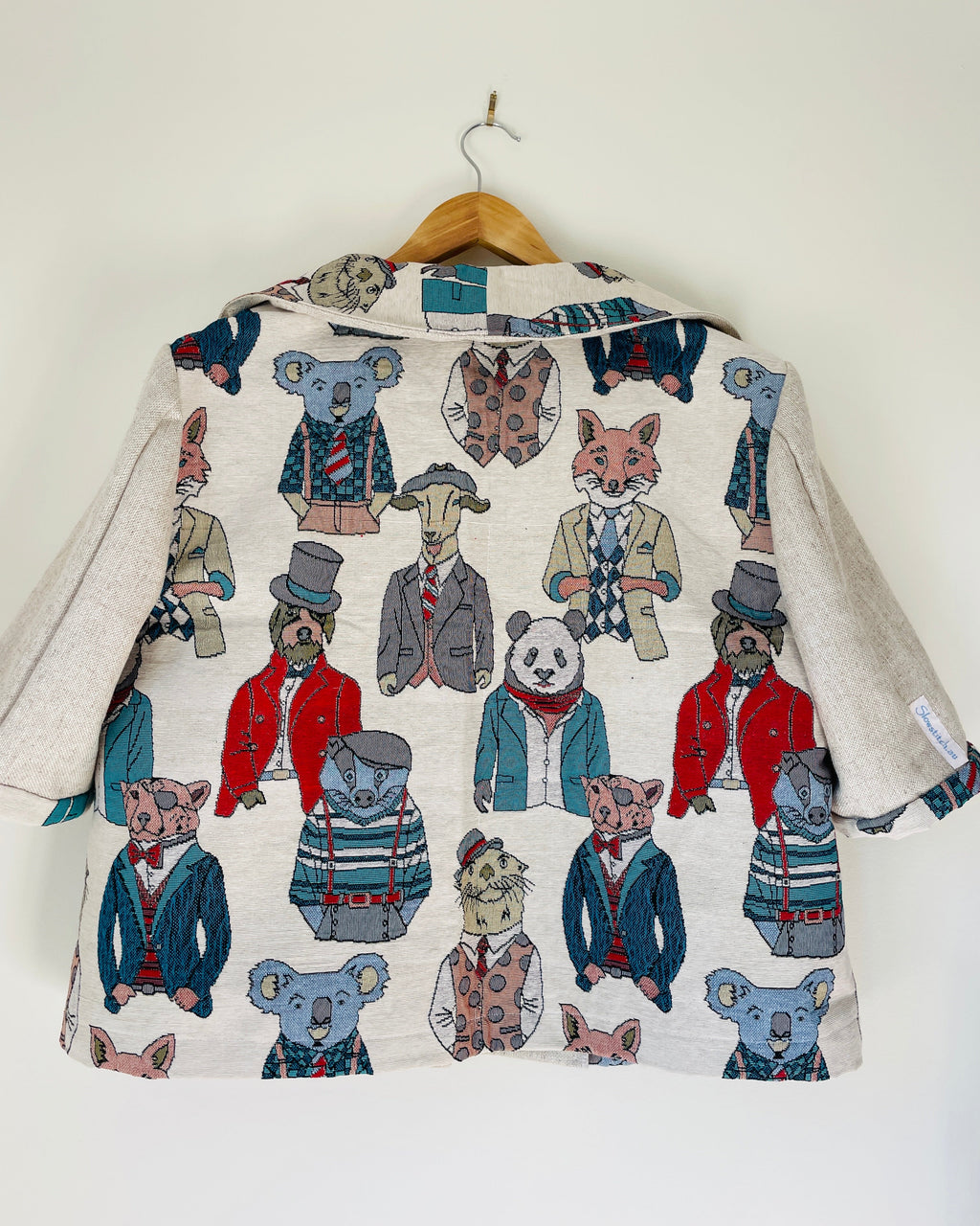 Jacket with animal print on a hanger against a white background