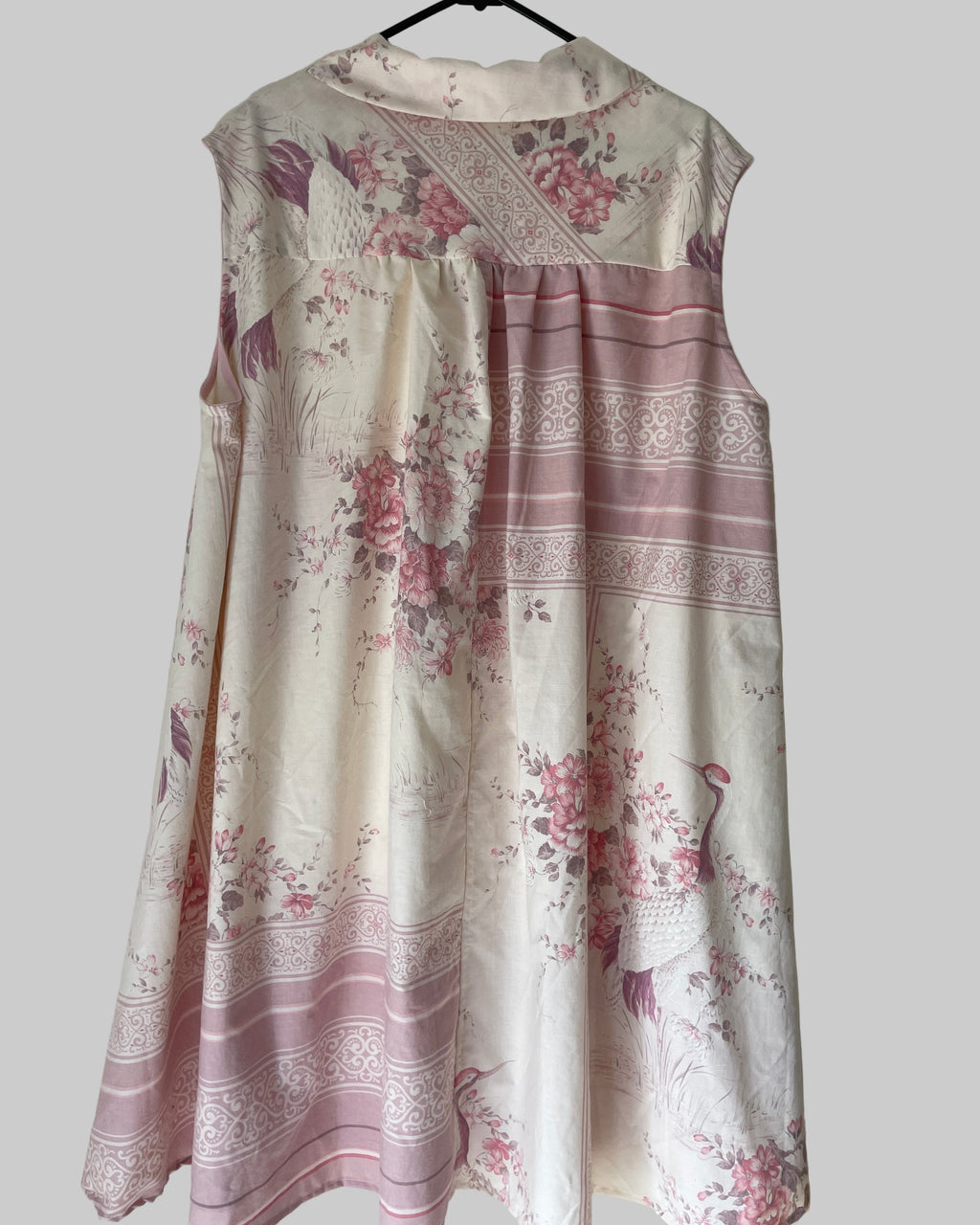 Floral dress with pink and white pattern on a hanger against a plain background