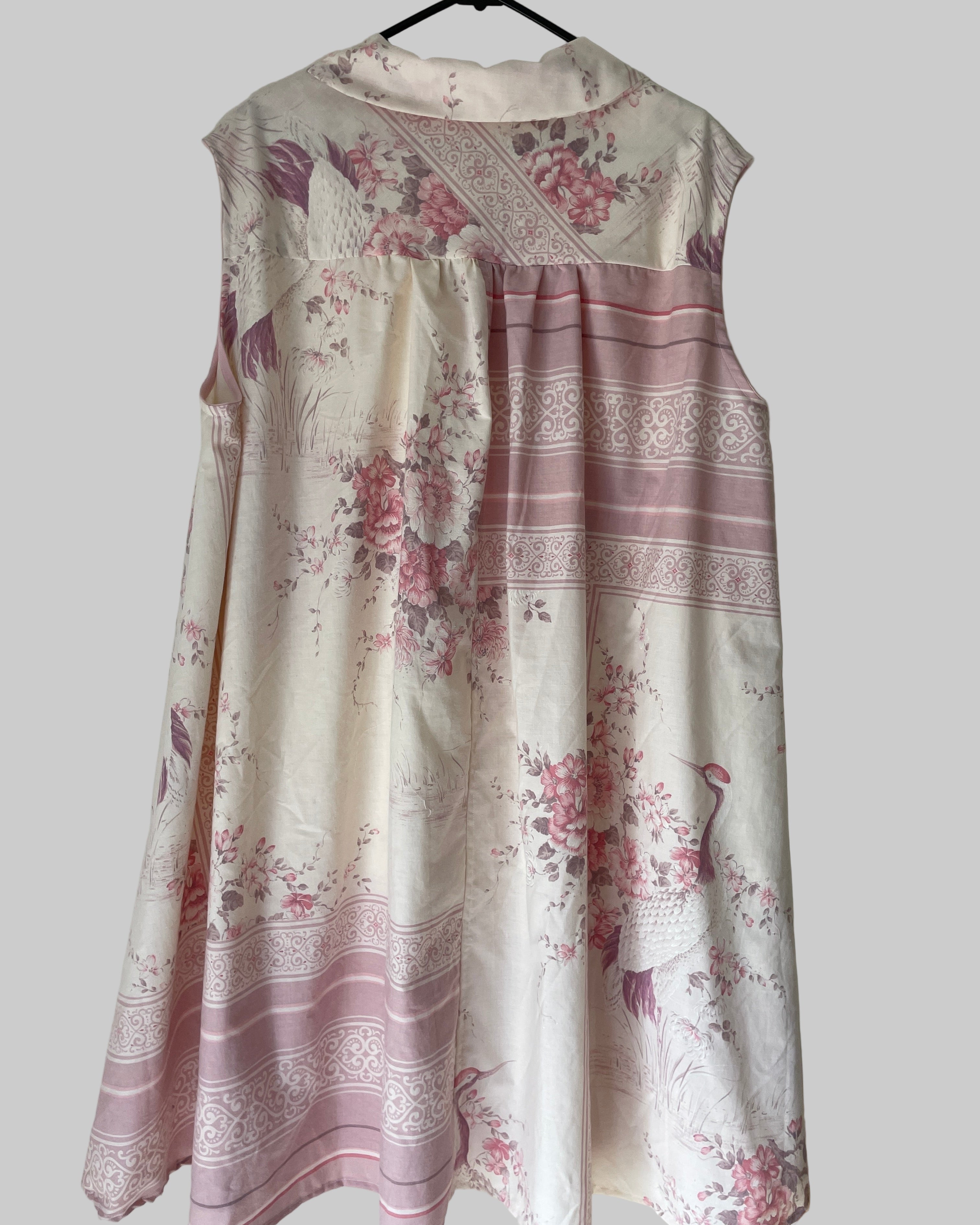 Floral dress with pink and white pattern on a hanger against a plain background
