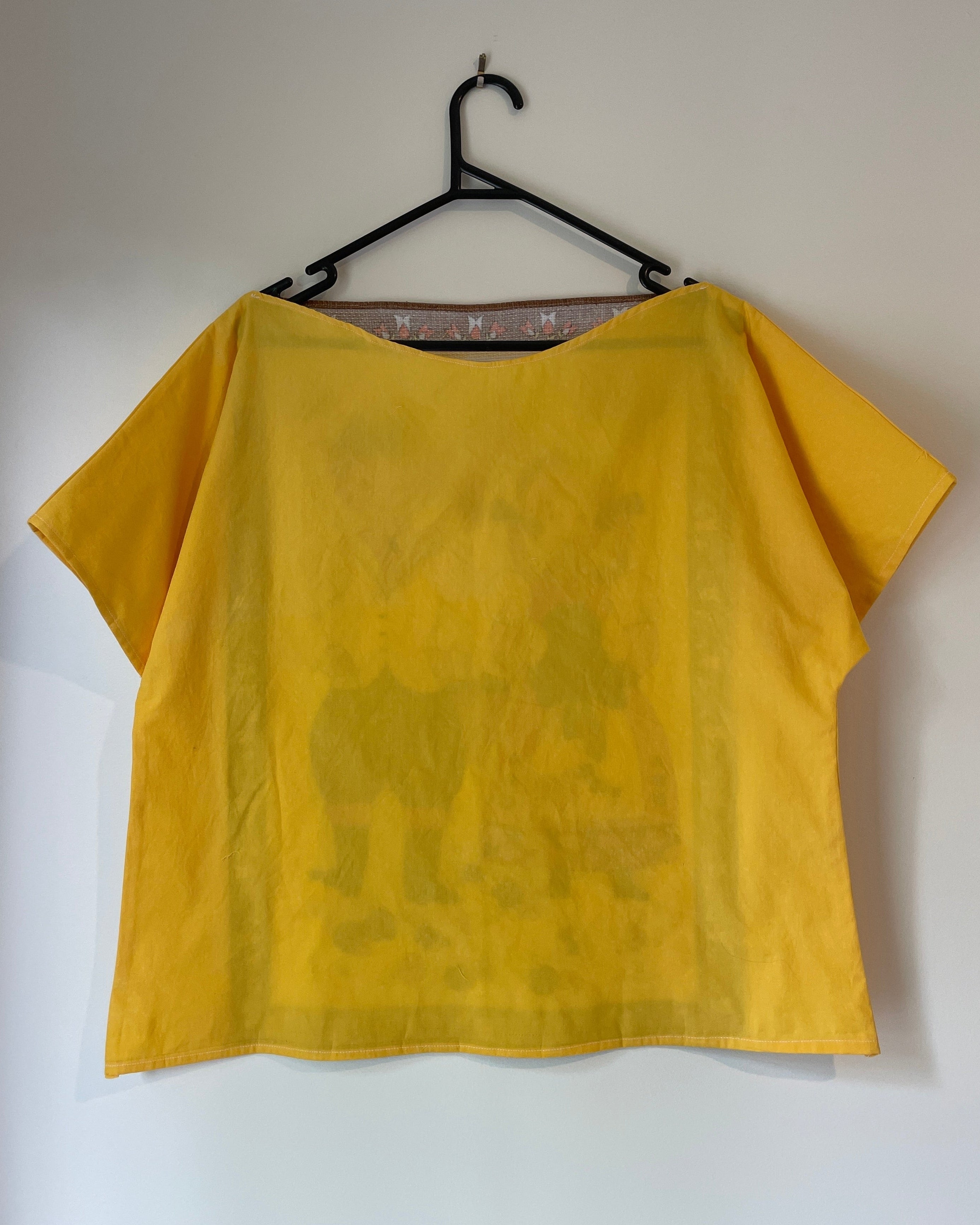 Yellow top on a hanger against a white wall