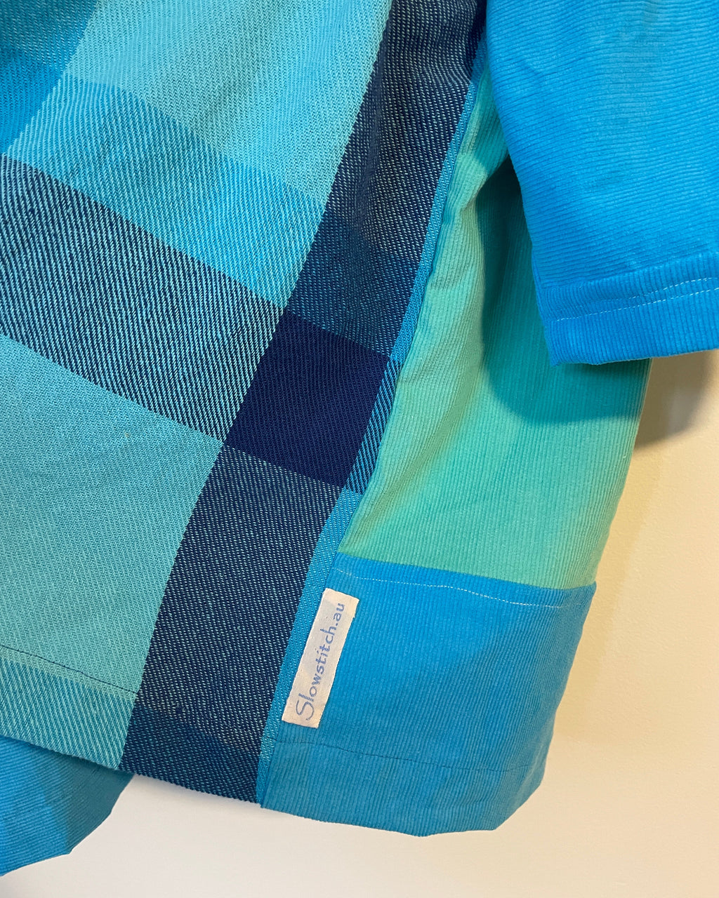 Close-up of a blue and green checkered jacket with a brand label.