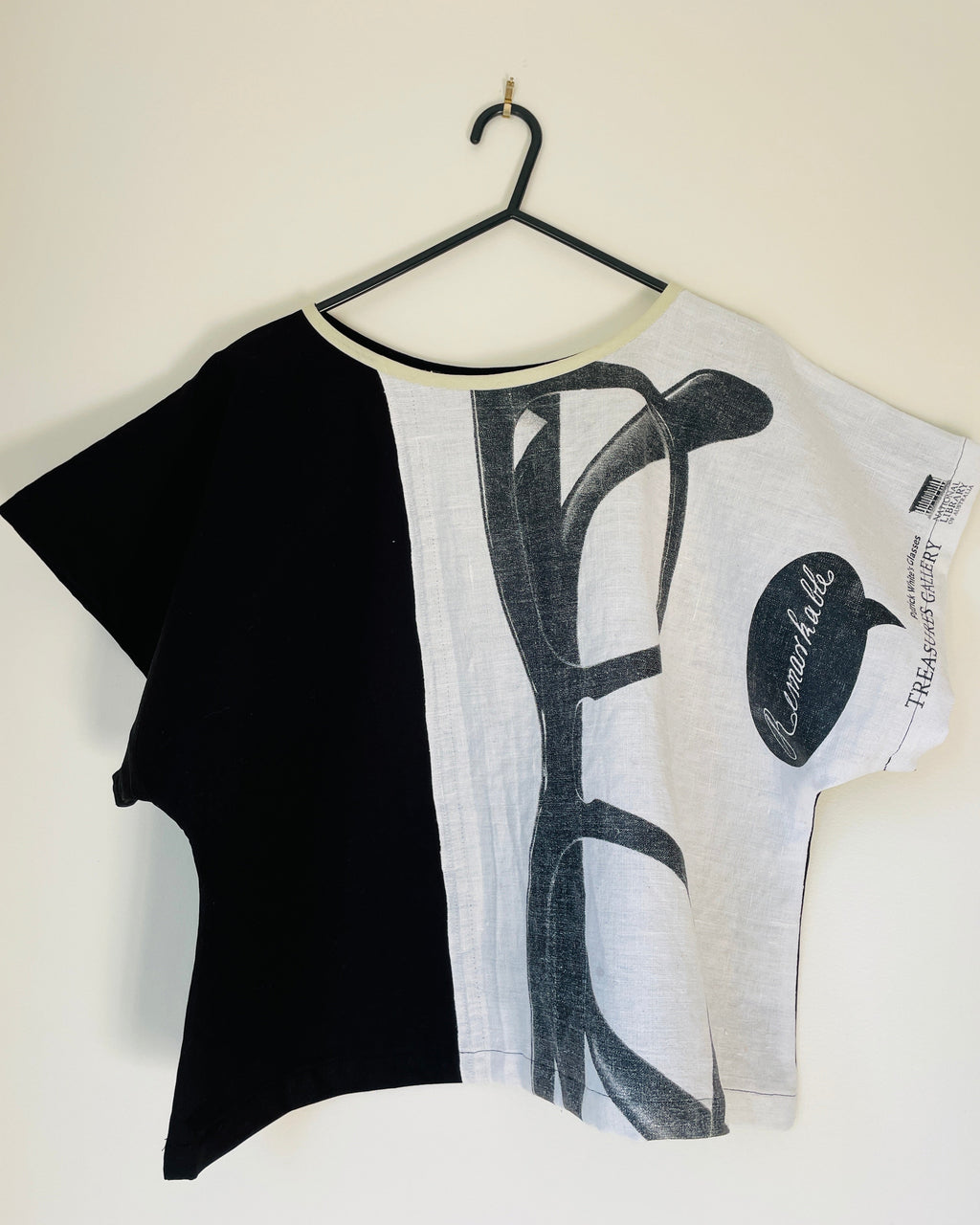 Black and white t-shirt with abstract design on a hanger against a white background