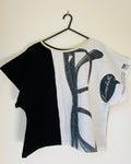 Black and white t-shirt with abstract design on a hanger against a white background