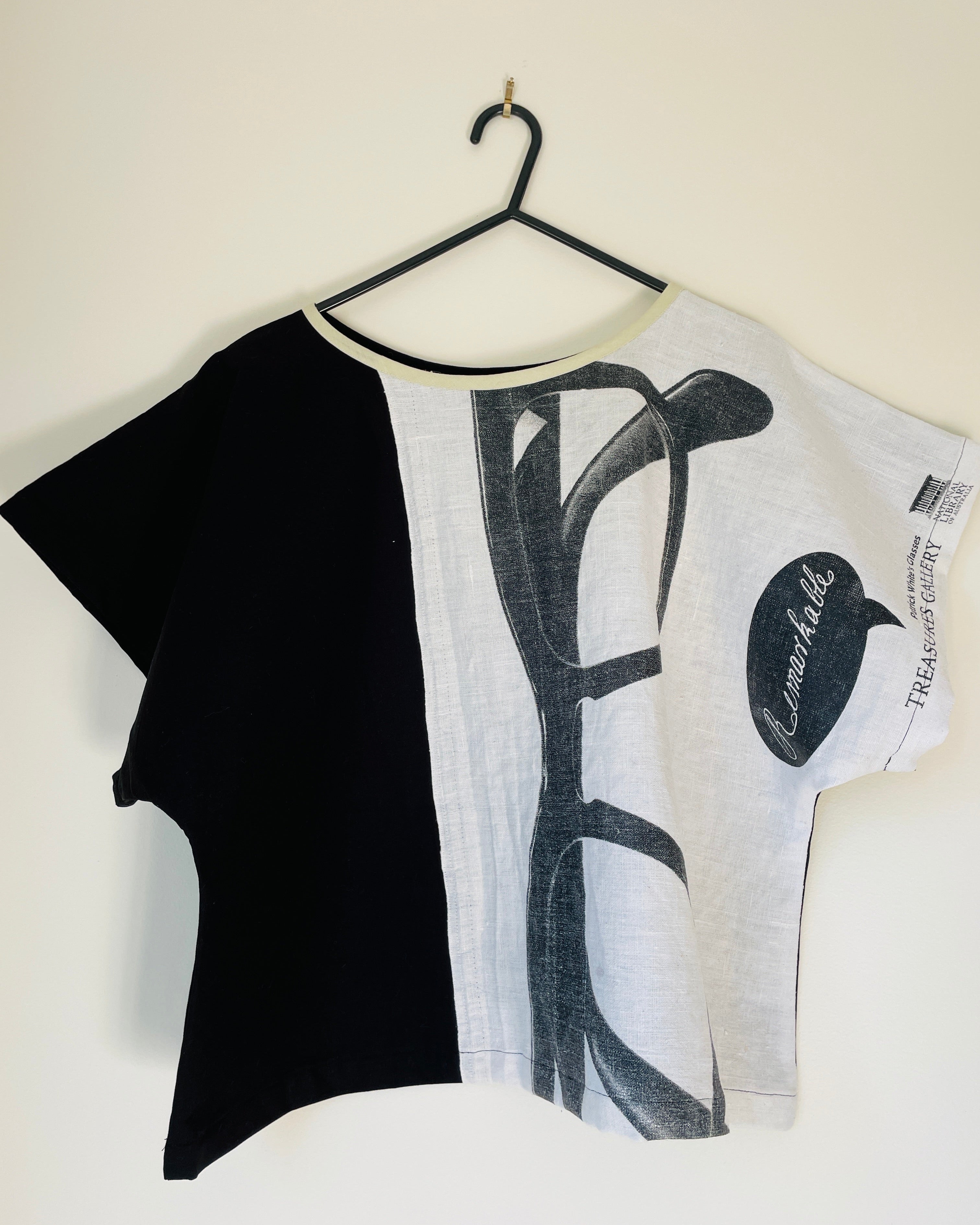 Black and white t-shirt with abstract design on a hanger against a white background