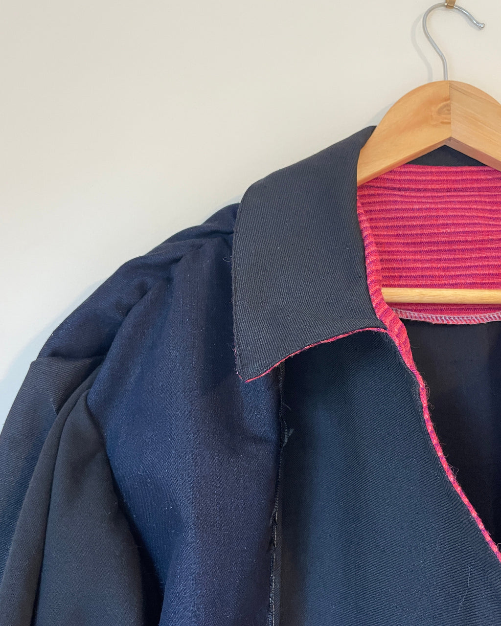 Close-up of a navy blue garment with pink stitching on a white background