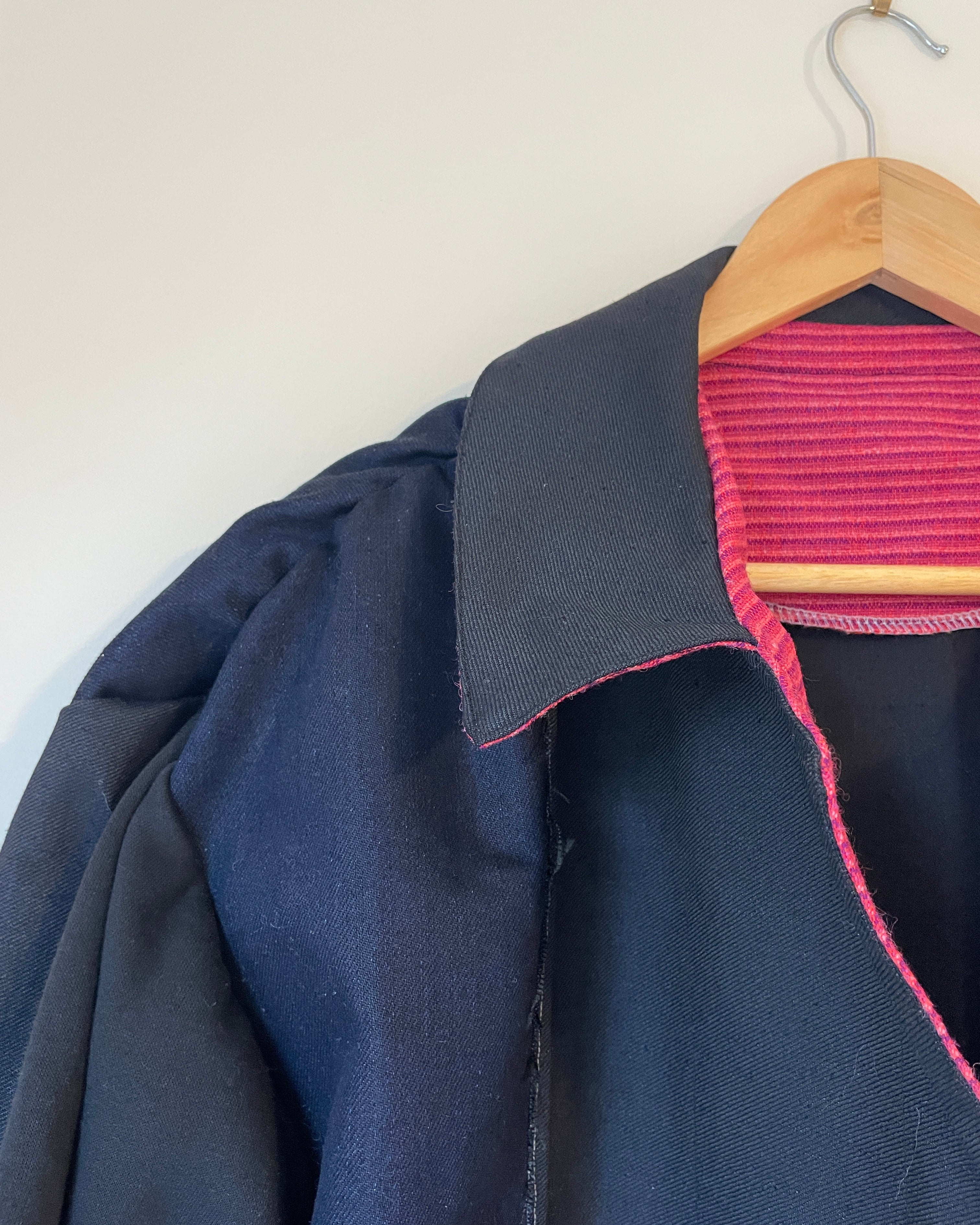 Close-up of a navy blue garment with pink stitching on a white background