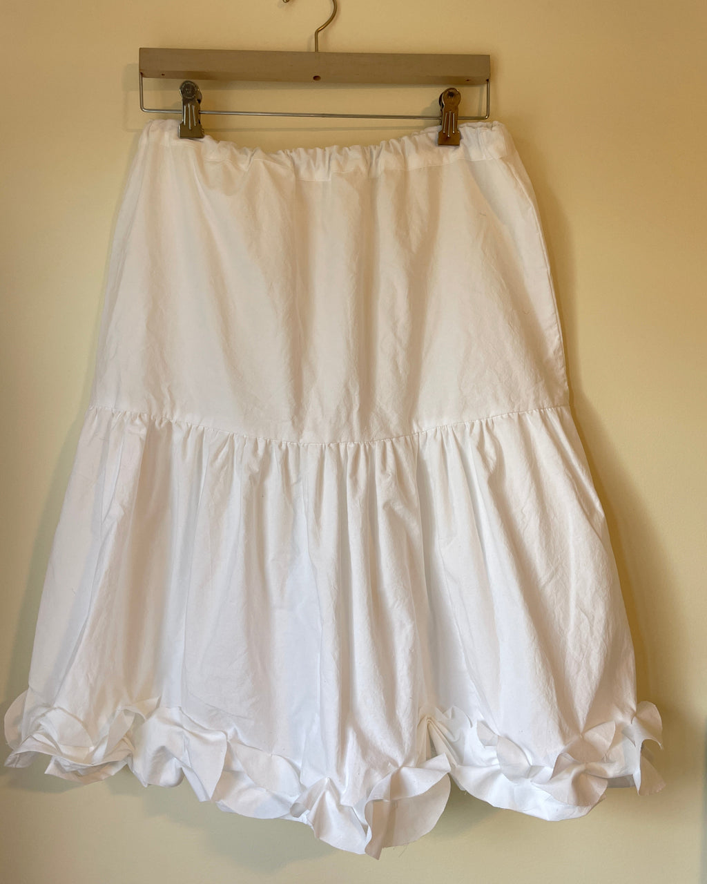 White dress on a hanger against a beige wall