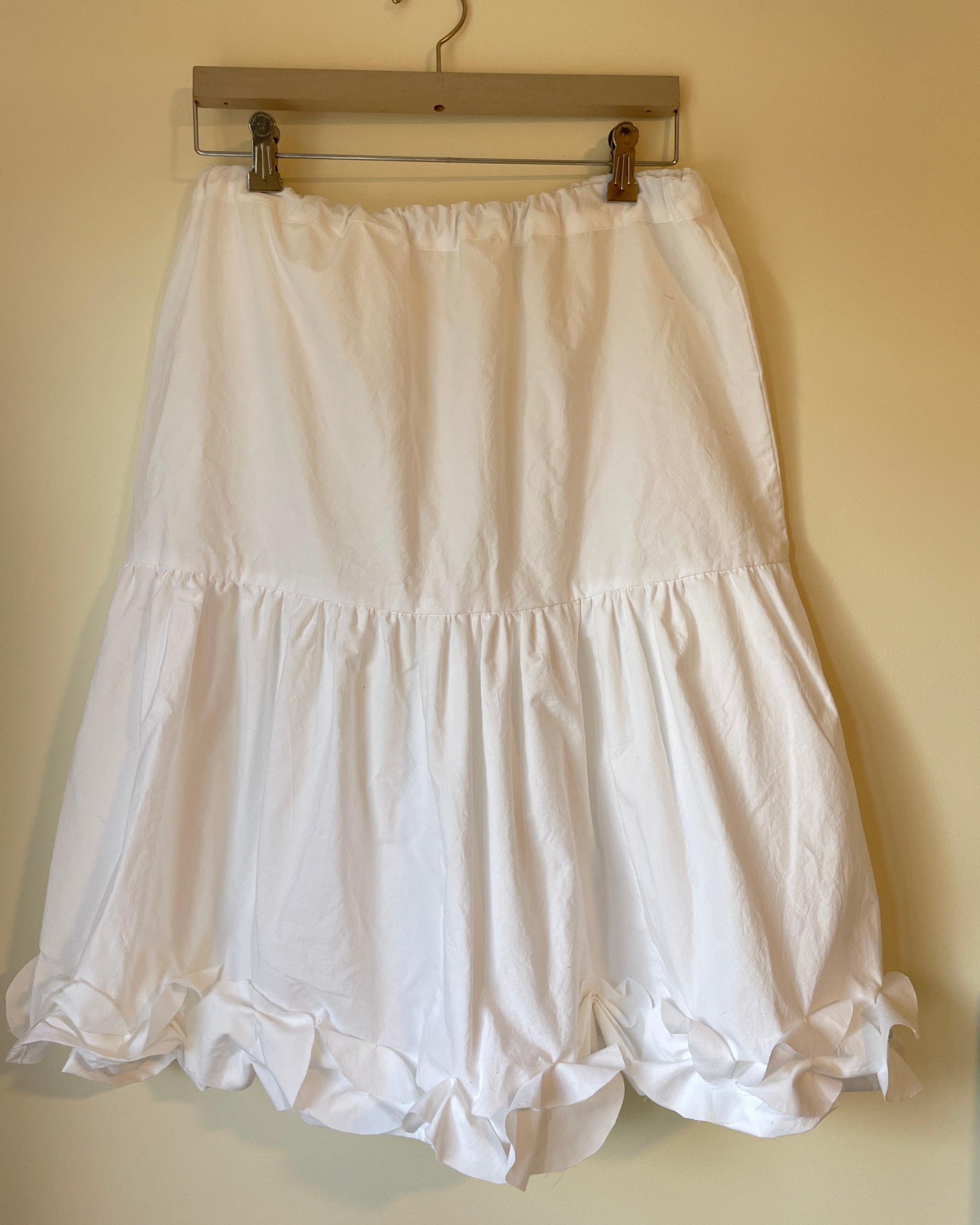 White dress on a hanger against a beige wall