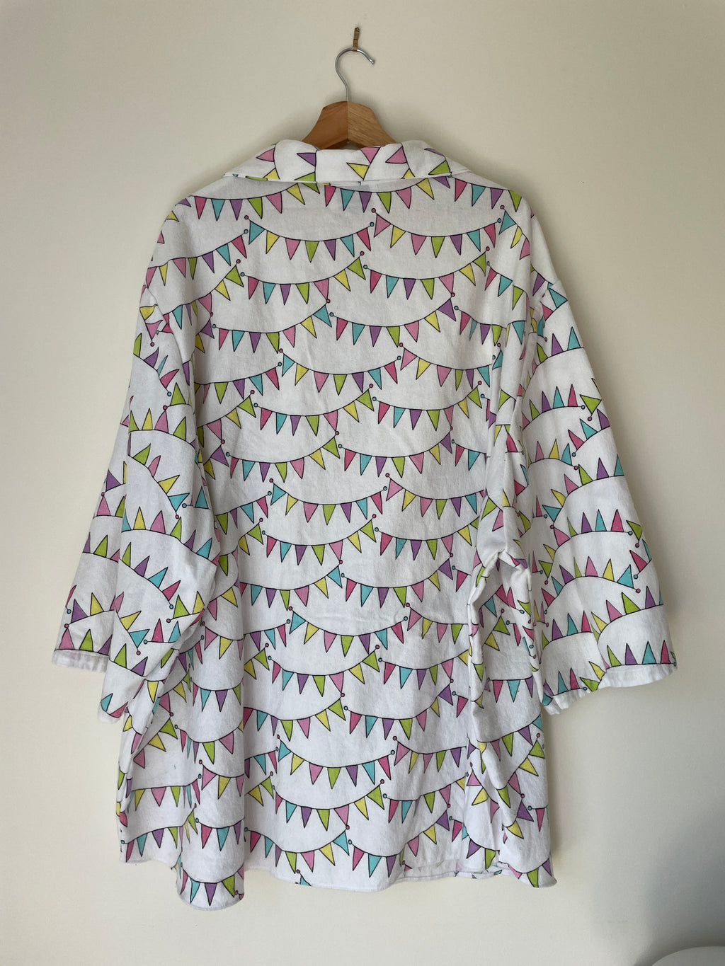 White shirt with colorful pattern on a hanger against a white wall