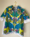 Colorful floral-patterned jacket on a hanger against a beige wall