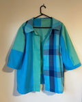 Blue and green plaid jacket on a hanger against a beige wall.
