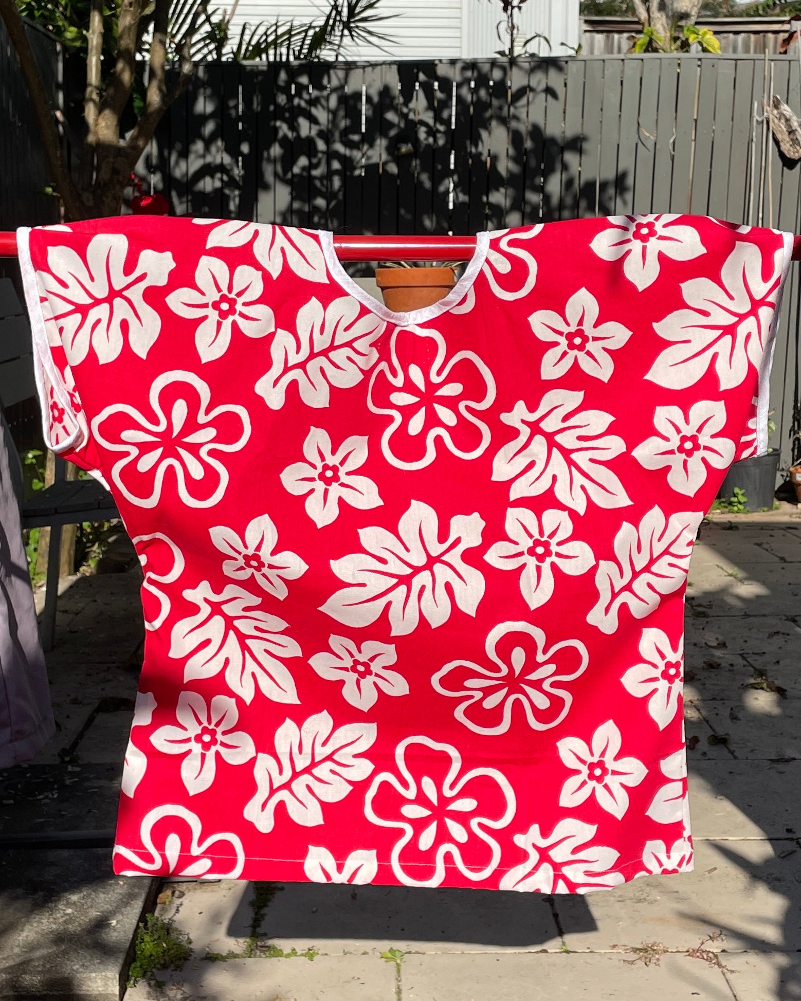 Red garment with white floral pattern on a wooden surface outdoors