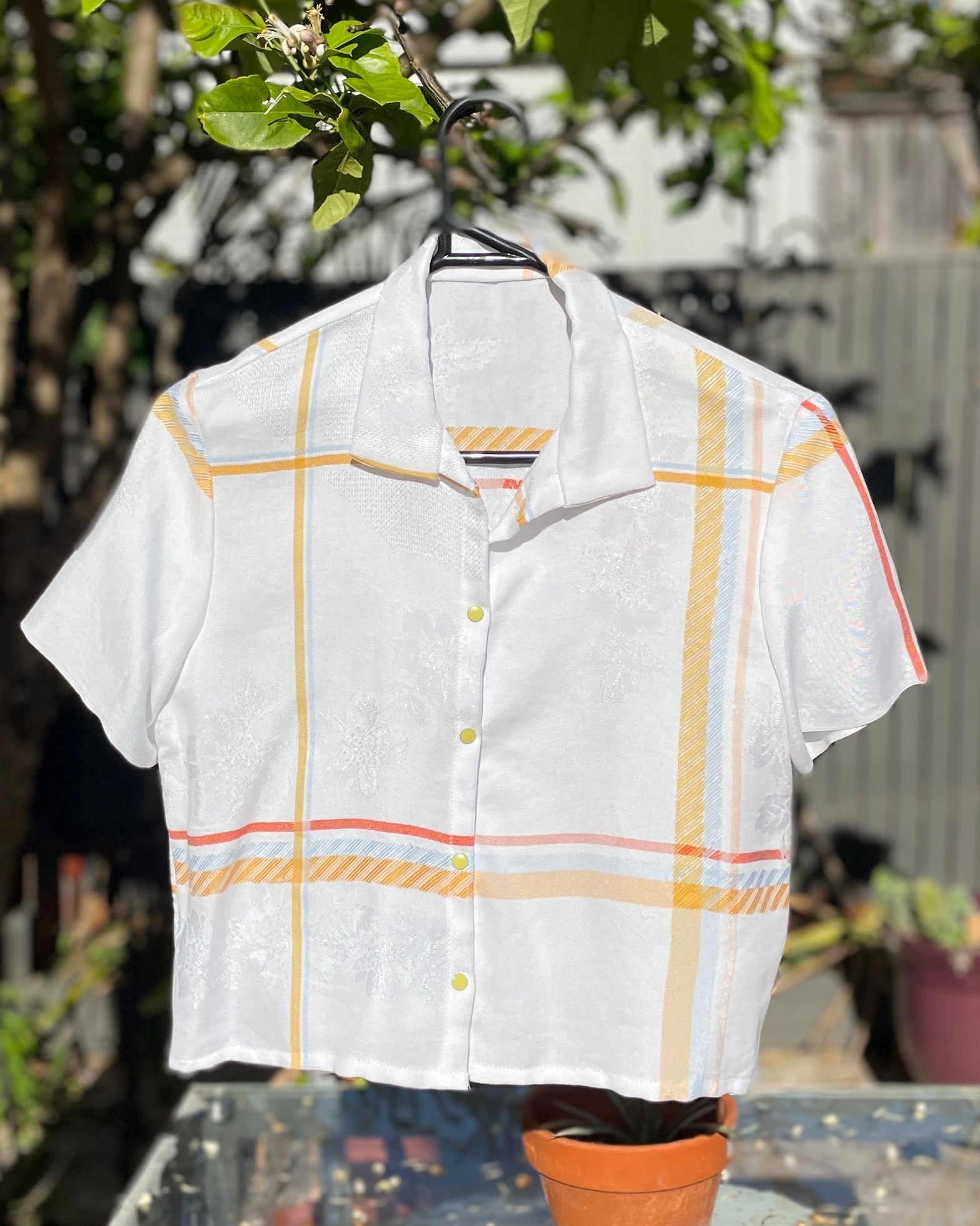 White shirt with yellow plaid pattern on a hanger