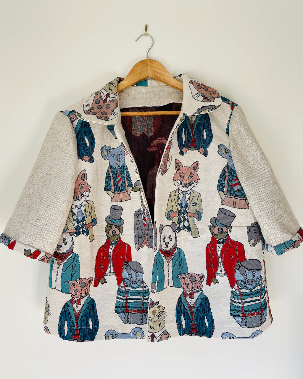 Jacket with animal-themed design on a hanger against a white background