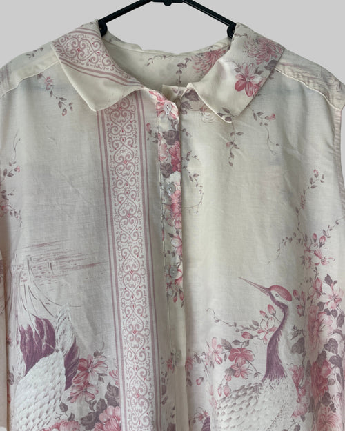 Floral and bird patterned dress on a hanger against a white background