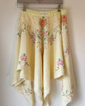 Embroidered floral skirt hanging on a rack against a white wall