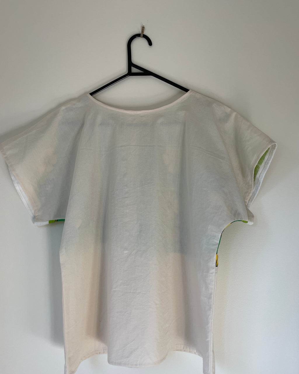 Cream coloured sleeveless top on a hanger against a white background