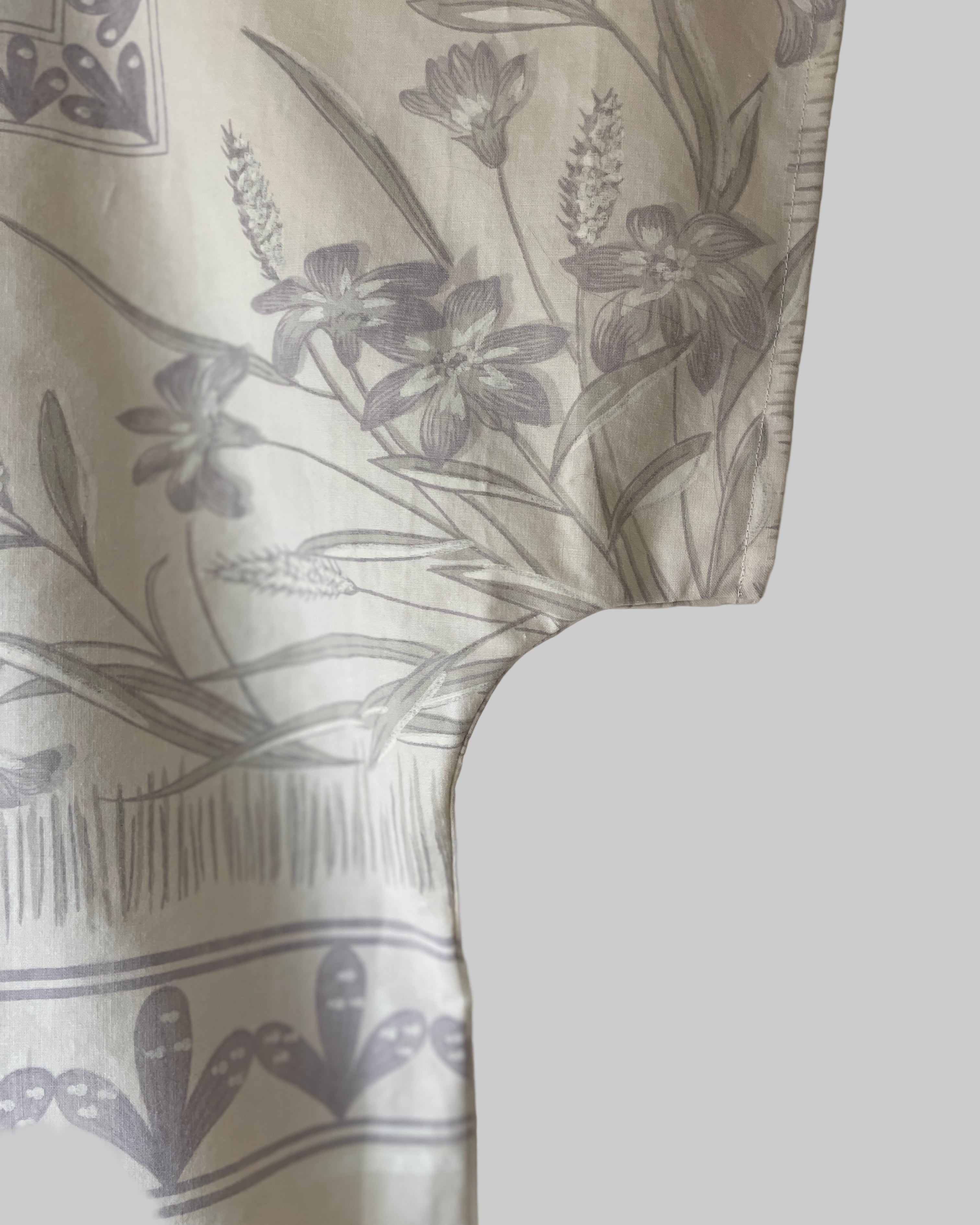 Greyish floral pattern on a cream plain background