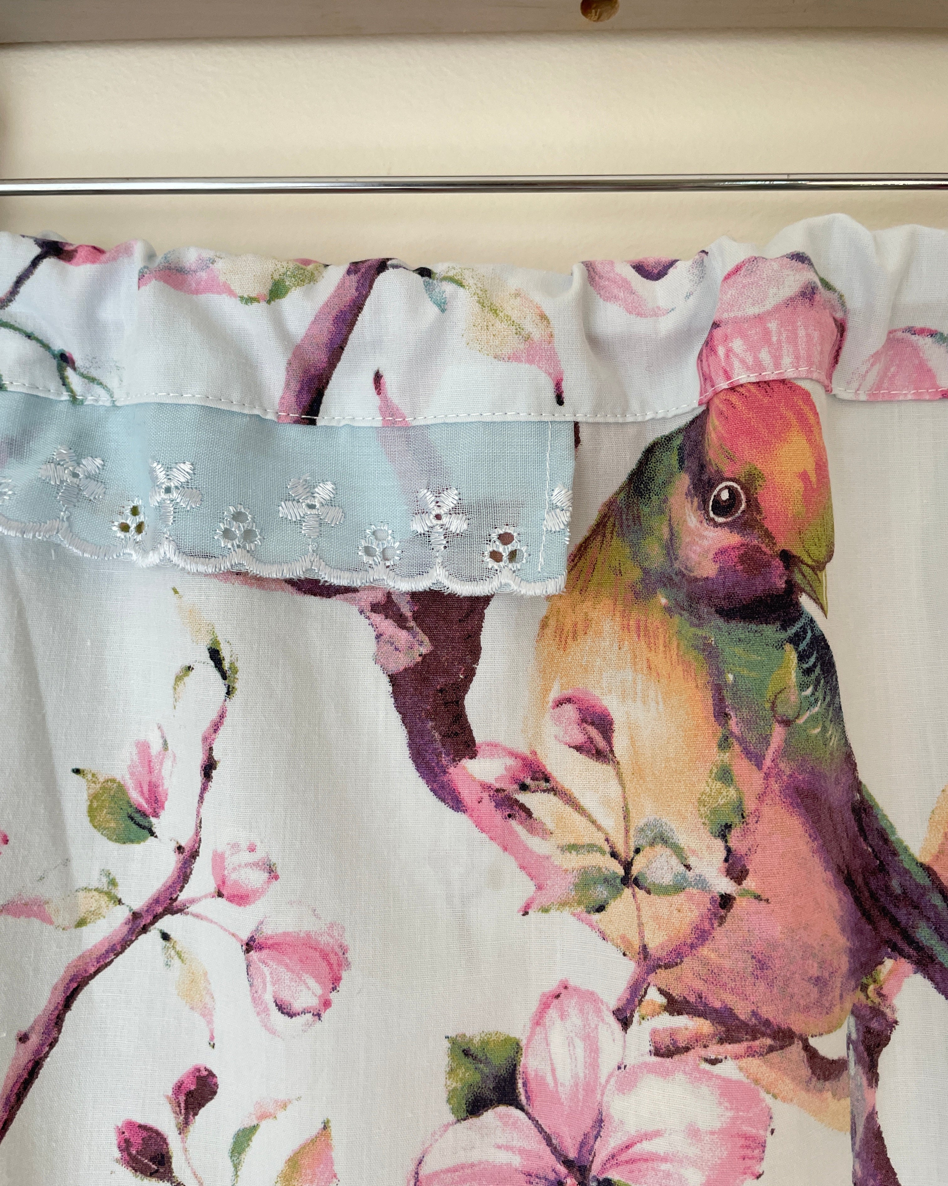 Floral and bird patterned fabric with a decorative trim on a white background
