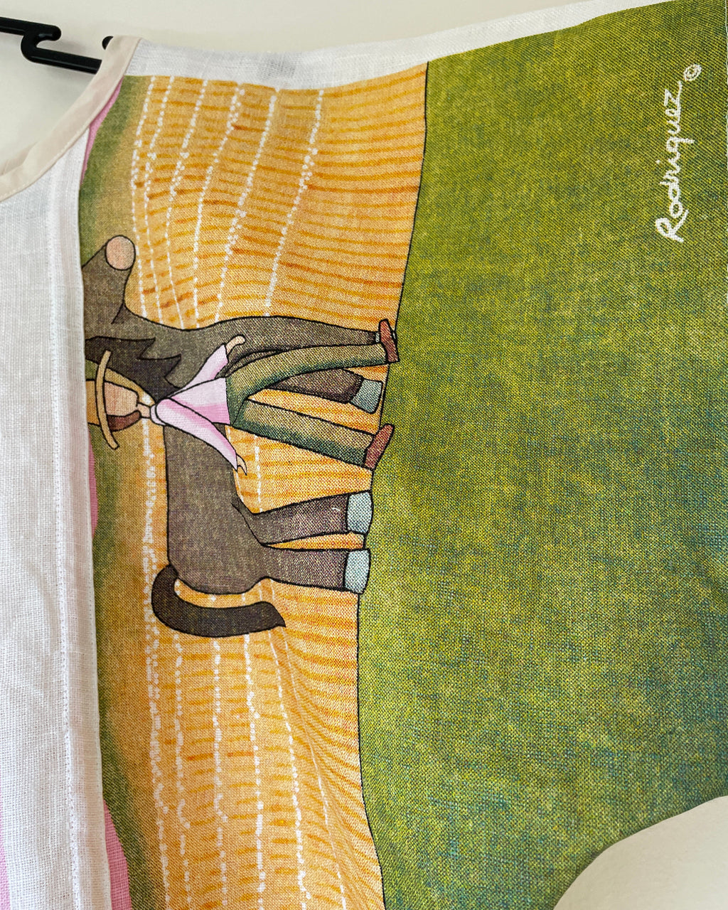 Textile art piece with a stylized landscape and figures, featuring a green sky and brown earth.