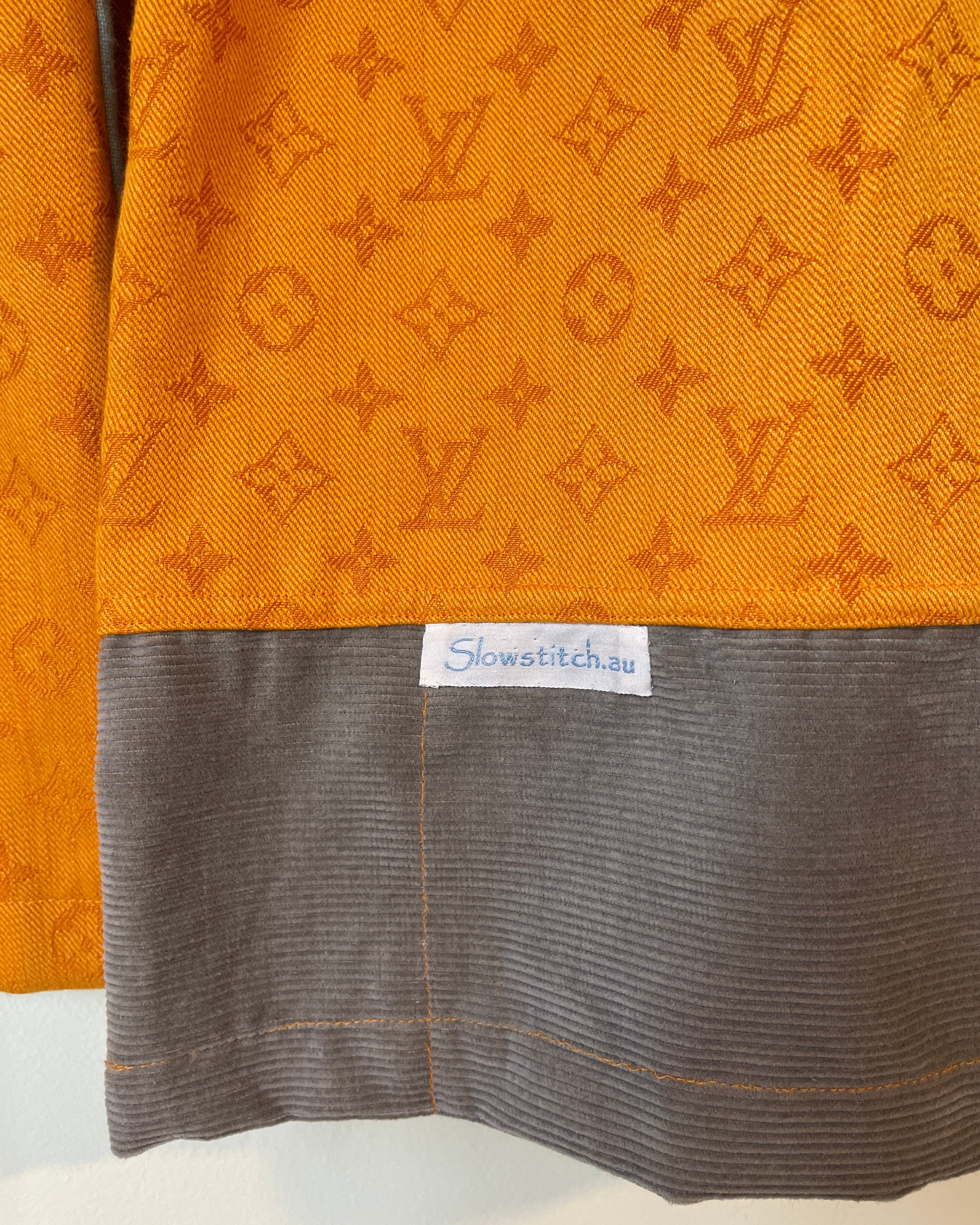 Close-up of orange fabric with a pattern and a gray fabric with a brand label.