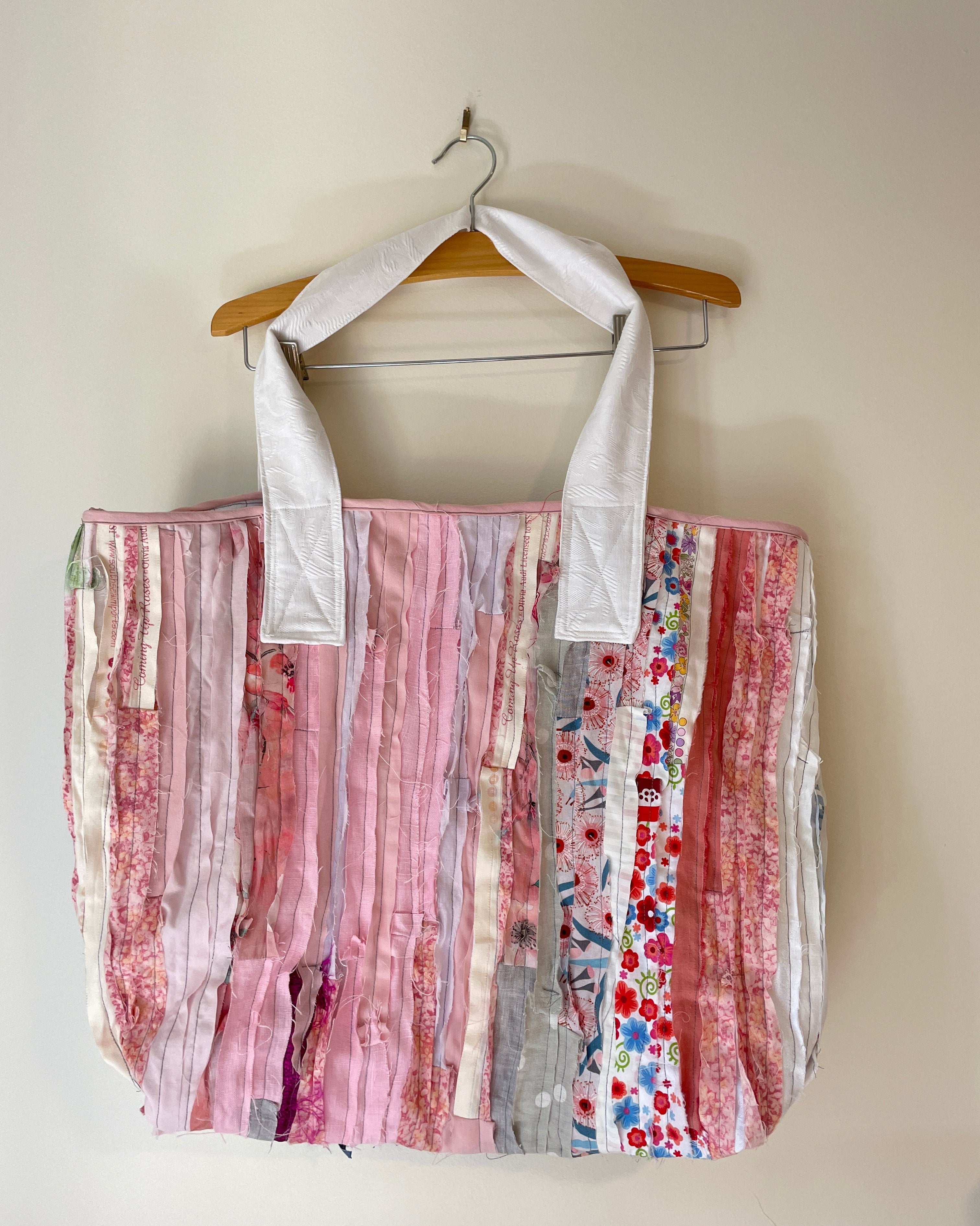 Tote bag on a wooden hanger against a beige wall.