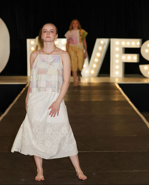 Model walking on a runway with 'MVFS' sign in the background