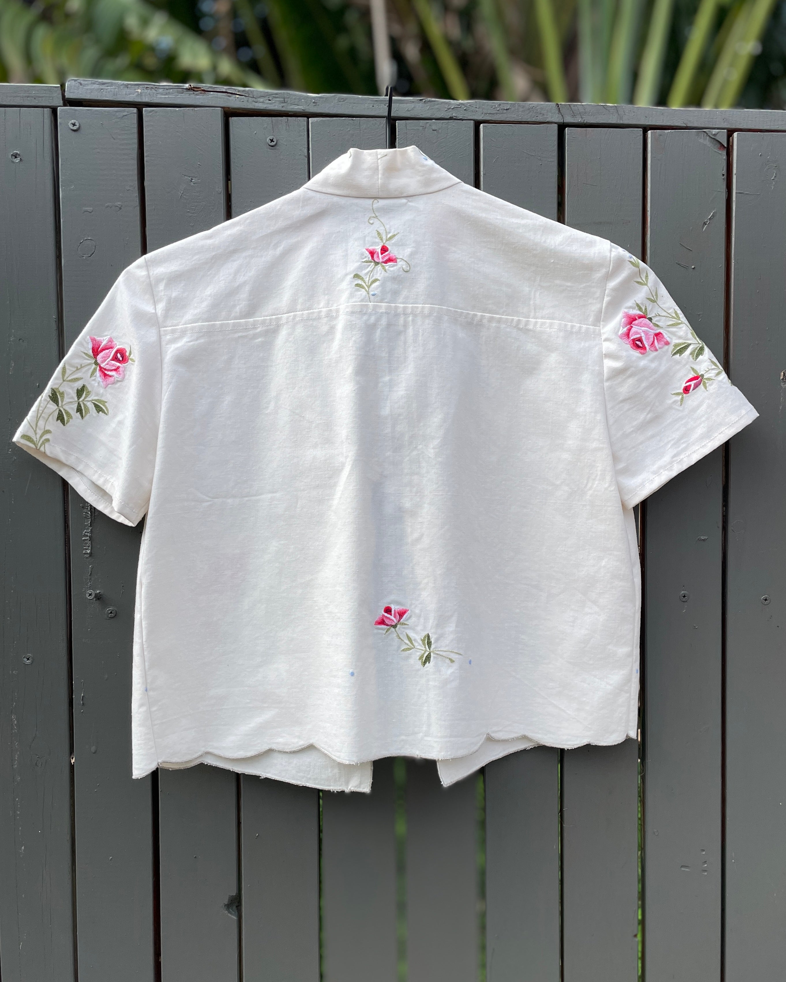 White shirt with floral embroidery on a wooden fence
