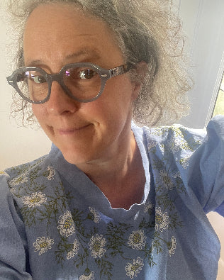 Person wearing glasses and a floral-patterned shirt with a neutral background